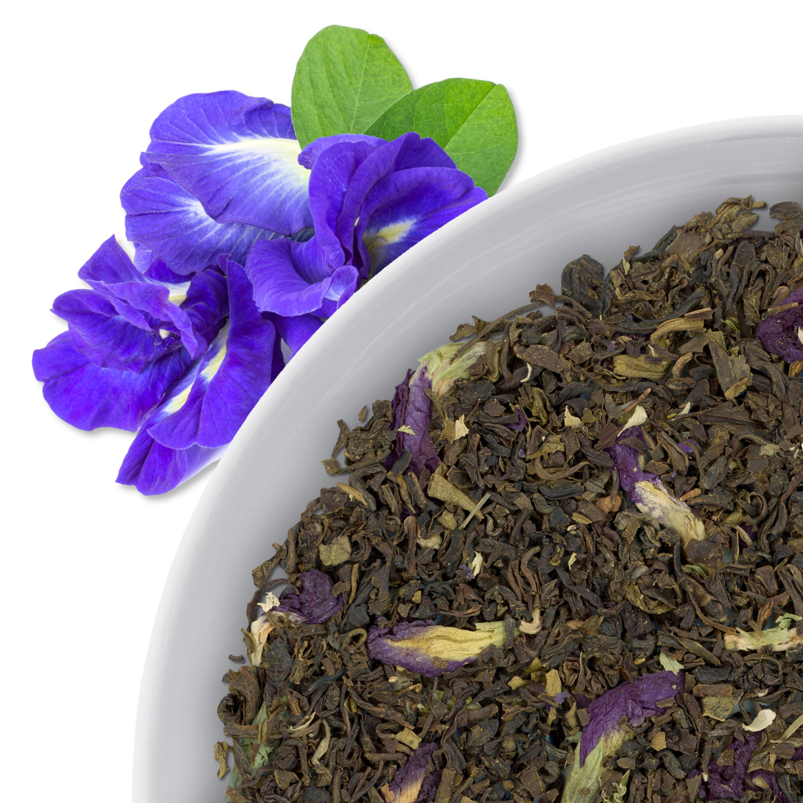 The corner of a bowl of Cerulean Dream loose leaf green tea, with flavor notes displayed through the use of blue pea flowers.