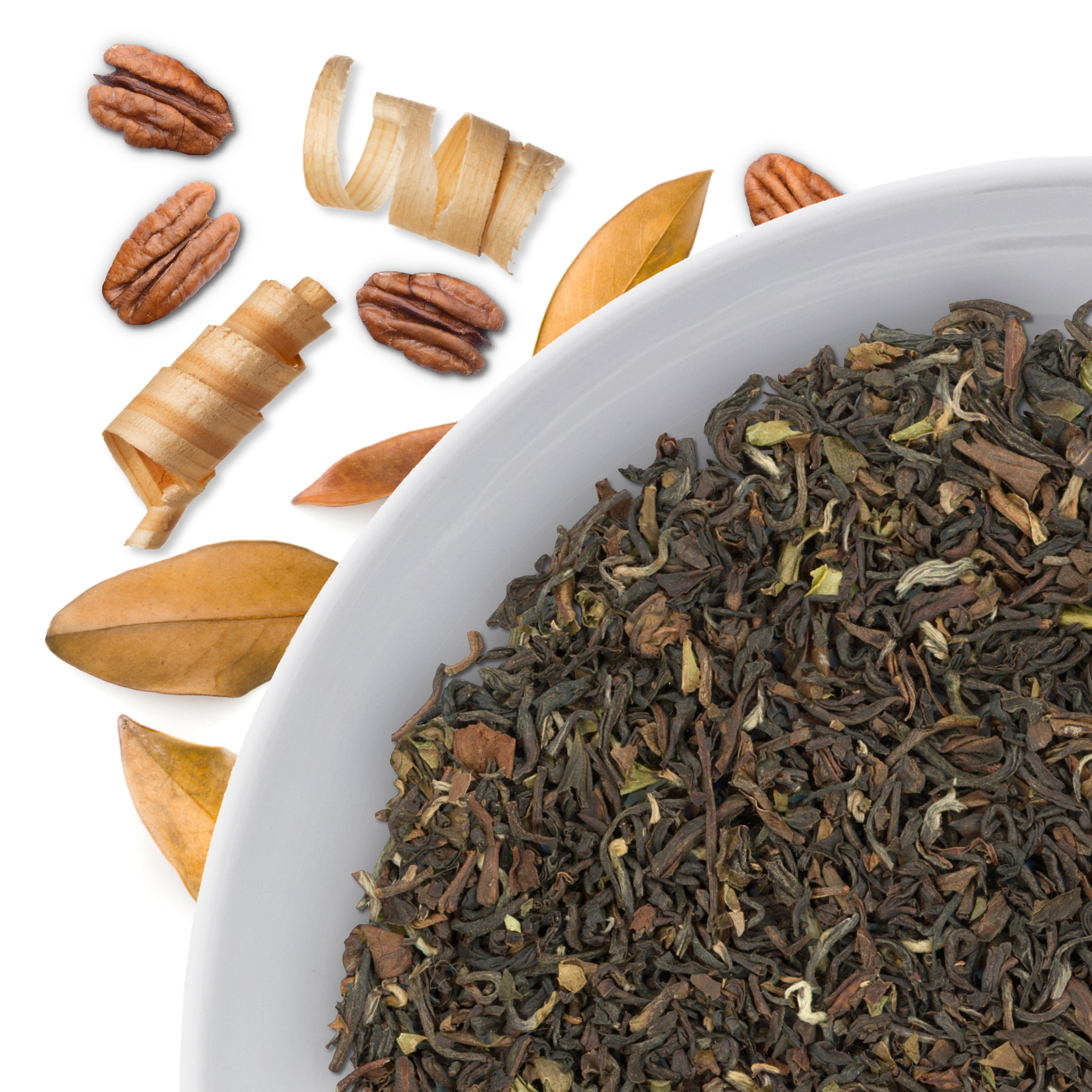 The corner of a bowl of Golden Forest loose leaf tea, with flavor notes displayed as woody and nutty through the use of scattered pecans, wood shavings and autumn leaves.